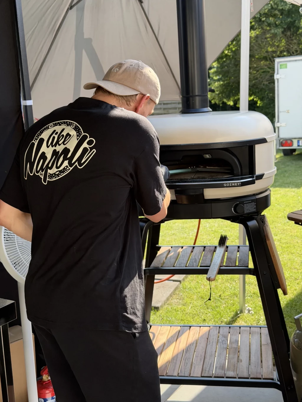 Pizzabäcker von Like Napoli am mobilen Pizzaofen unter dem Pavillon einer Gartenparty in Leveste
