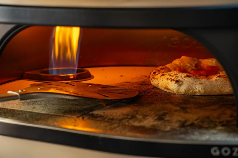 Neapolitanische Pizza backt neben der offenen Flamme im Gasofen