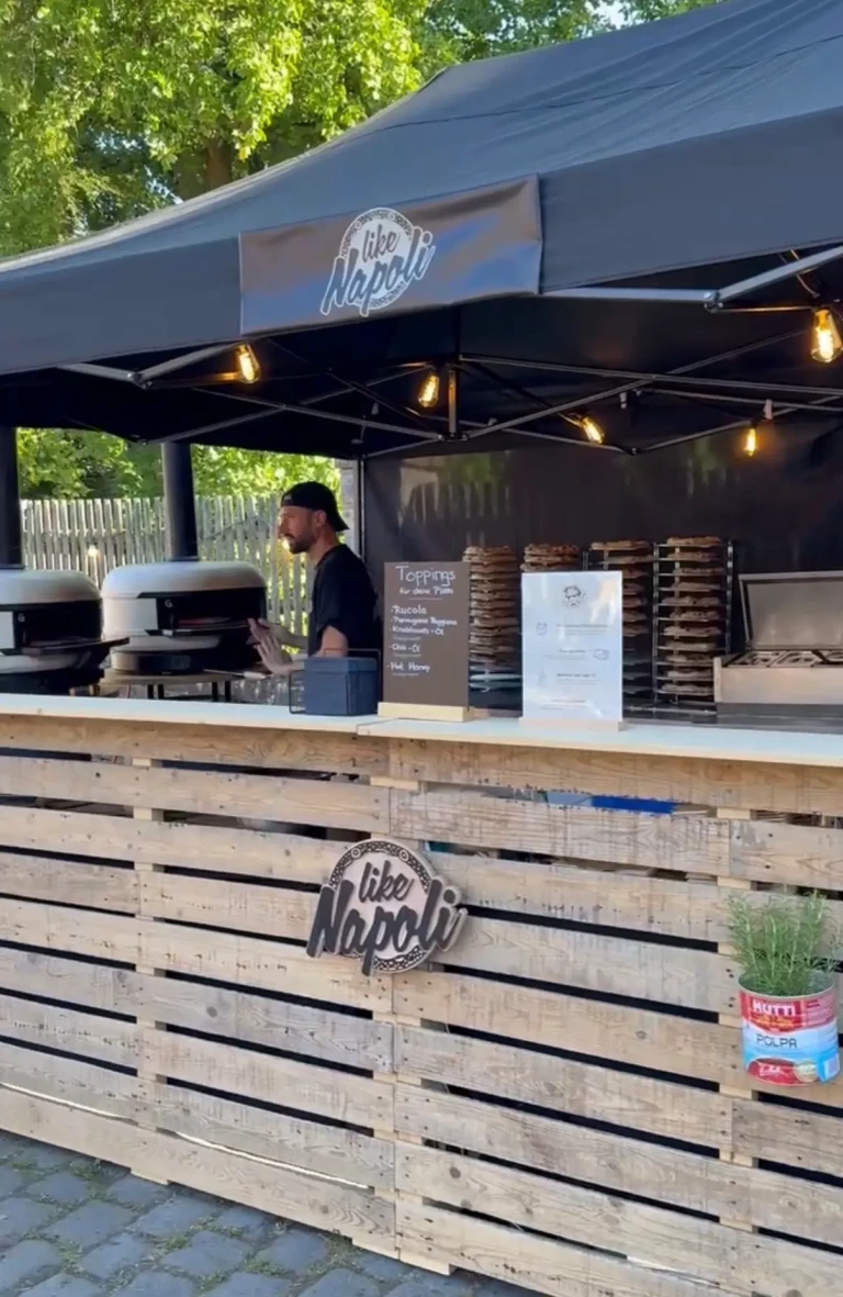 Pizzastand mit Palettentheke und zwei Pizzaöfen unter schwarzem Pavillon bei der Weinwanderung Wennigsen